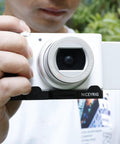 Person holding camera with L-Shaped Grip For Sony ZV-1 II And ZV-1F Vlog Cameras With Black ARCA Extension Bracket and Quick Release Plate