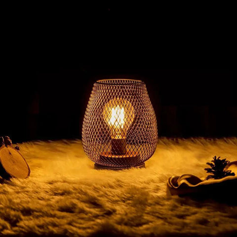 Set Of 4 Battery Operated LED Table Lanterns In Rustic Brown Metal Cage glowing on fur surface, creating vintage ambiance.