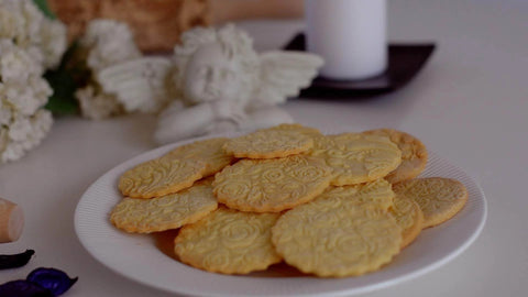 Plate of cookies with embossed patterns made using the Beech Wood Embossed Rolling Pin With Butterflies And Flowers For Cookies And Crafts Handmade Kitchen Tool For Beautiful Patterns Ideal Gift For Mom Or Best Friend Great For Bakers And Hobbyists.