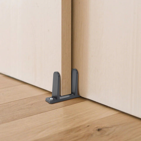 4-Piece Black Closet Door Floor Guide Set With Screws And Screwdriver For Smooth Sliding Closet Doors Fits 1-3/8 Inch Thick Doors Includes Floor Guides, Durable Hardware For Easy Installation installed under a wooden door.