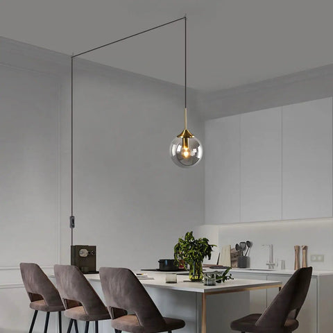 Mid Century Modern Brushed Gold Pendant Light With Plug In Cord, Smoke Gray Glass Globe over kitchen island
