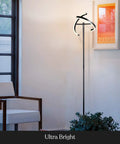 Halo Split LED Torchiere Floor Lamp Dimmable Bright Light Tall Standing Lamp For Living Room Or Office With Adjustable Rotating Light Rings Jet Black Finish And Modern Easy Style in a modern living room next to a white chair and art print.