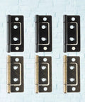 Six Pack Thickened Flat Door Hinges in Black and Bronze on light brick wall background