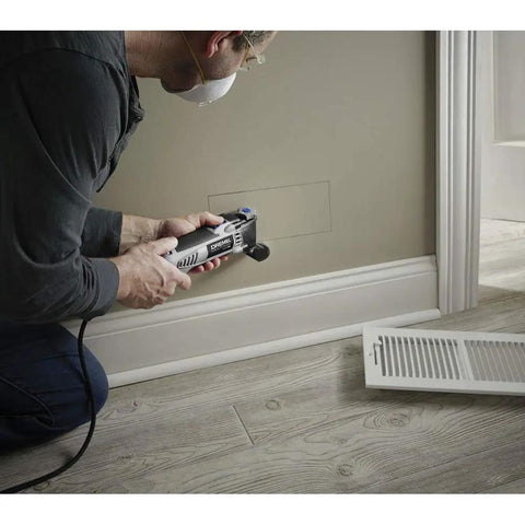 Man using Pro Grade Corded Oscillating Multi Tool Kit 120V 3.5 Amp Power, Reconditioned, for cutting wall near floor vent
