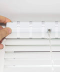 Close-up of hand inserting Clear 20 Pack Valance Clips for Horizontal Blinds into track for secure window treatment.