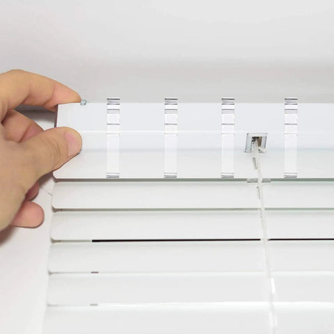 Close-up of hand inserting Clear 20 Pack Valance Clips for Horizontal Blinds into track for secure window treatment.