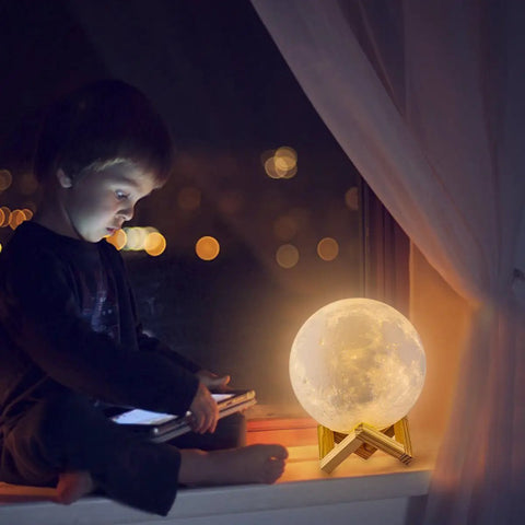 Child reading by Moon Lamp 7 Inch 3D Printed Moon Light With Stand, 16 Color LED Night Light on windowsill
