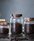 Keep Your Stash Fresh With These Top Notch Sealed Tea Canisters And Coffee Bean Jars Crafted From Durable Glass Super Simple Kitchen Pantry Storage Essentials That Are Actually Worth The Buy Hella Convenient. Three glass jars with wooden lids holding coffee beans.