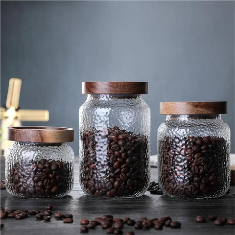Keep Your Stash Fresh With These Top Notch Sealed Tea Canisters And Coffee Bean Jars Crafted From Durable Glass Super Simple Kitchen Pantry Storage Essentials That Are Actually Worth The Buy Hella Convenient. Three glass jars with wooden lids holding coffee beans.