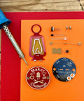 DIY Soldering NiteLight Lantern Maker Kit parts on display, includes PCB, resistor, transistor, and soldering iron for students and adults.