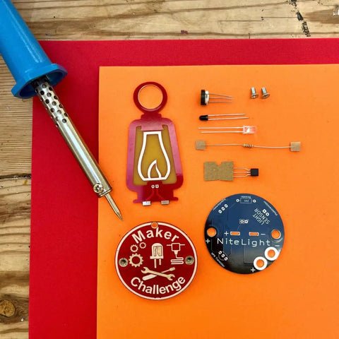DIY Soldering NiteLight Lantern Maker Kit parts on display, includes PCB, resistor, transistor, and soldering iron for students and adults.