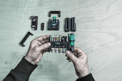 Hands holding Tool Check Modular 1 21 Piece Screwdriving Set Ultra Compact Pro Grade Versatile Kit with components visible on table.