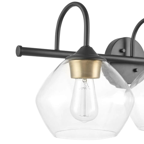 Close-up of Lofty Chic Three Light Vanity Light in dark bronze with clear glass shade and antique brass accents for bathrooms