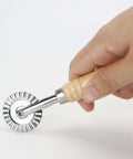 Side view of a handheld pizza cutter wheel with fluted zinc-alloy blade and wooden handle, 16 cm long
