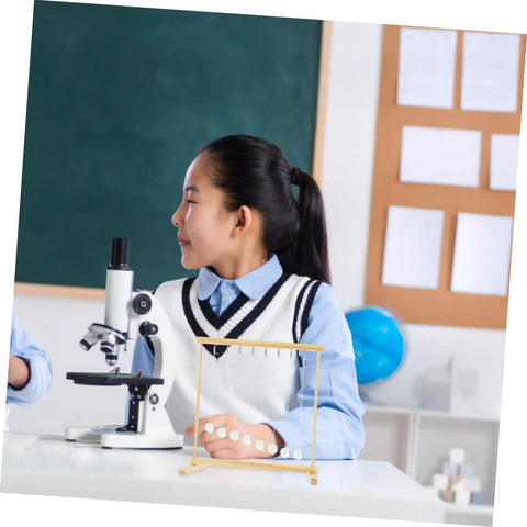Student in classroom using Hands On Energy Conservation Science Kit with a snake shape pendulum next to a microscope.