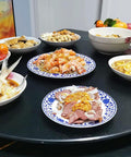 Top Shelf 31 Inch Black Tempered Glass Lazy Susan Turntable with various dishes including shrimp and meat on the dining table.