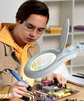 Person using LED Magnifying Lamp With Clamp, 1,200 Lumens, 5-Inch Glass Lens, 2.25x Magnification for electronics repair