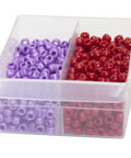 Plastic storage box with clear dividers separating purple and red beads.