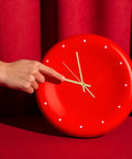 A hand adjusts gold clock hands on a red clock face from Metal Clock Hands Replacement Kit 10 Sets Handy DIY Wall Clock Hands for repair.