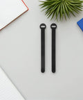 Super Solid 100 Piece Pack Of Self Adhesive Nylon Cable Ties With Cute Round Heads on a grey surface with notebooks.