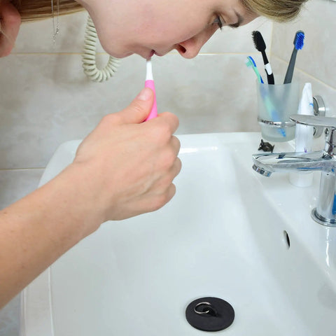 Person brushing teeth in bathroom sink with Four Piece Tub Stopper Set With Hanging Ring Rubber Drain Plugs For Tub Sink Kitchen And Bathroom In Black Fits One And One Eighth To One And Seven Eighths Inch Drains Durable Easy To Install Replacement For Worn Out Plugs