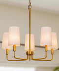 Modern gold chandelier with white fabric shades, featuring a sleek design, ideal for contemporary dining spaces.