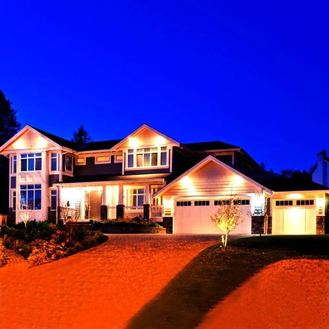 JUDYSSY Outdoor Solar Flood Lights illuminating a modern home at night, highlighting architecture and landscape with soft glow.