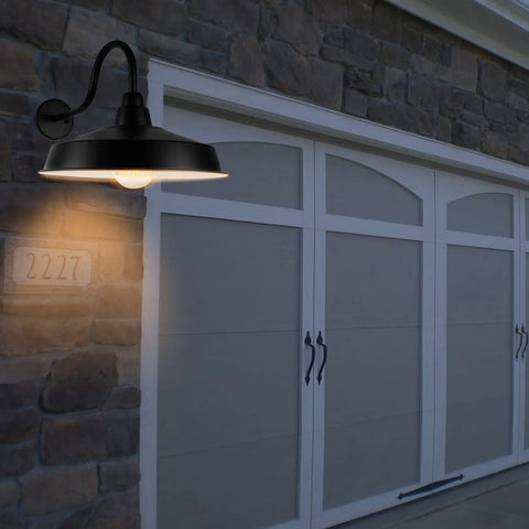 16 Inch Dome Barn Light Outdoor Wall Mount Sconce illuminating a garage entrance with rustic brick wall backdrop.