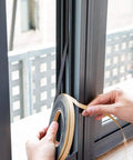Person applying Heavy Duty Neoprene Foam Seal Tape 3 Pack 1/2 Inch Wide By 1/8 Inch Thick 59 Feet Total on window frame.