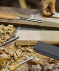Heavy Duty 16 Piece Wood Carving Tool Set With Premium Handles Sharp Chisels And Gouges Includes Wooden Mallet And Whetstone on a workshop table.