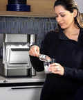 GE Profile Opal 2.0 Ultra nugget ice maker in stainless steel on kitchen counter with clear ice bin and scoop included