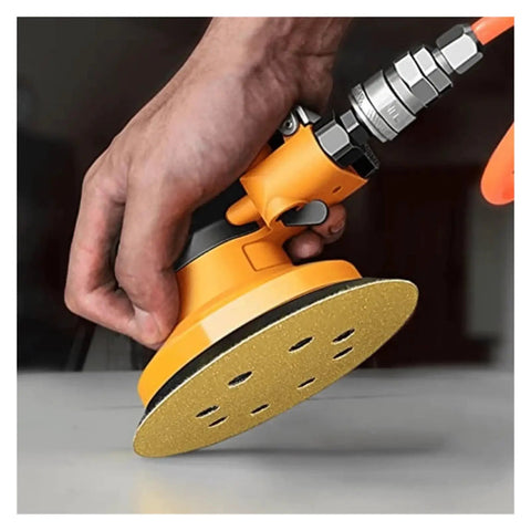 Hand holding a 5 inch orbital sander with a yellow hook loop sanding disc, showcasing fast dust extraction for smooth polishing.