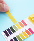 Person using 80 Strips Pack PH Tester Strips Full Range 1 to 14 Litmus Paper for chemistry experiments with color chart visible