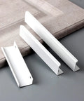 Six Pack Finger Edge Drawer Pull Handles In Bright White, three aluminum handles on grey surface, highlighted hidden mount design.