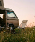 Capy Ultralight Camping Chair For Backpacking And Festivals beside a camper van in a scenic outdoor setting at sunset.
