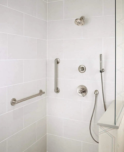 Modern shower with stainless steel fixtures, including grab bars, handheld showerhead, and controls on tiled wall.