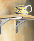 Heavy Duty Folding Triangle Wall Brackets For Custom Corner Shelves, built like a tank holding a shelf with a teapot.