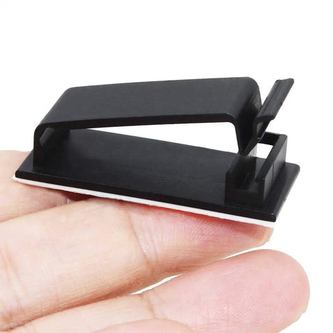 50 Pack Self Adhesive Cable Clips For TV PC And Ethernet Cables Under Desk, black polyamide clip on hand, close-up view.