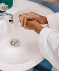 Heavy Duty Rubber Drain Stopper With Sturdy Pull Ring, Six Piece Set Of White Sink Plugs That Slickly Fit Most Bathtub And Kitchen Drains Daily in a bathroom sink with hands washing.