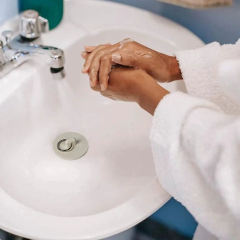 Heavy Duty Rubber Drain Stopper With Sturdy Pull Ring, Six Piece Set Of White Sink Plugs That Slickly Fit Most Bathtub And Kitchen Drains Daily in a bathroom sink with hands washing.