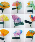Nine handmade colorful paper flowers with names on tags, arranged in a 3x3 grid, showcasing creative designs.