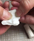 Hands holding a white cotton fiber tab, part of the 48 Pack Fire Starter Tabs Waterproof Tinder For Camping, Survival, And Campfire Ignition.