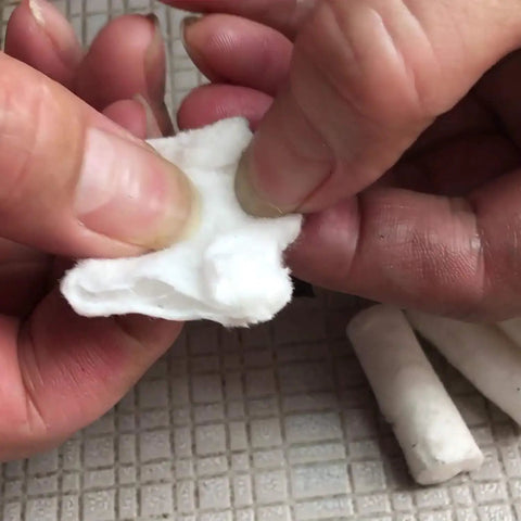 Hands holding a white cotton fiber tab, part of the 48 Pack Fire Starter Tabs Waterproof Tinder For Camping, Survival, And Campfire Ignition.
