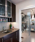 Modern kitchen with dark wood cabinets, stainless steel sink, and glass door leading to a wine room with racks filled with bottles.