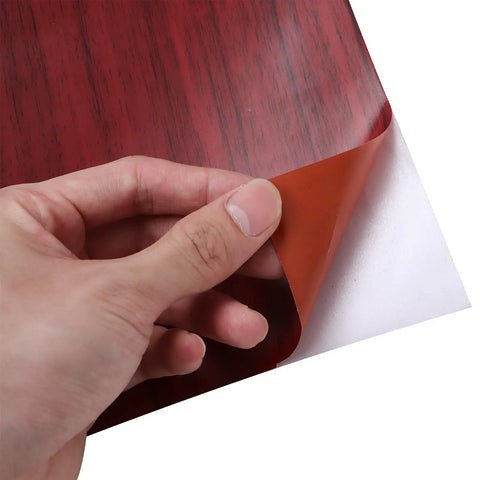 Glow Up Ready Peel And Stick Waterproof Wallpaper For Walls And Furniture Hella Easy Install Rustic Brown Vinyl Wrap being peeled back to reveal adhesive.