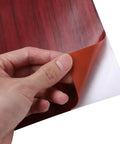 Self Adhesive Vinyl Wallpaper Roll For Kitchen Cabinets Showcasing Real Deal Wood Grain Pattern, peelable backing being removed.