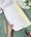 White Self Adhesive Eva Foam Roll 78.7 X 15.7 Inches 1 Mm Thick Craft And Upholstery Padding being cut with scissors on green surface.
