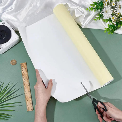 White Self Adhesive Eva Foam Roll 78.7 X 15.7 Inches 1 Mm Thick Craft And Upholstery Padding being cut with scissors on green surface.
