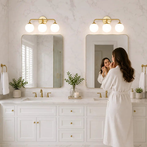 Dope Mid Century 3 Light Vanity Fixture With Smooth Brushed Gold Finish And Soft Milky White Glass Ball Shades For Sick Bedroom Bathroom Mirror Vibe, mounted over double mirrors in a modern bathroom.