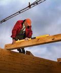 Worker using 48 Inch Type 196-2 Digital Tech Level Tool Boasting Dead Nuts Electronic Vials on a wooden beam at a construction site.